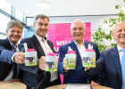 Hornegger, Herrmann, Söder und Thomas zeigen Tassen mit Motiven der Stadt-Umland-Bahn
