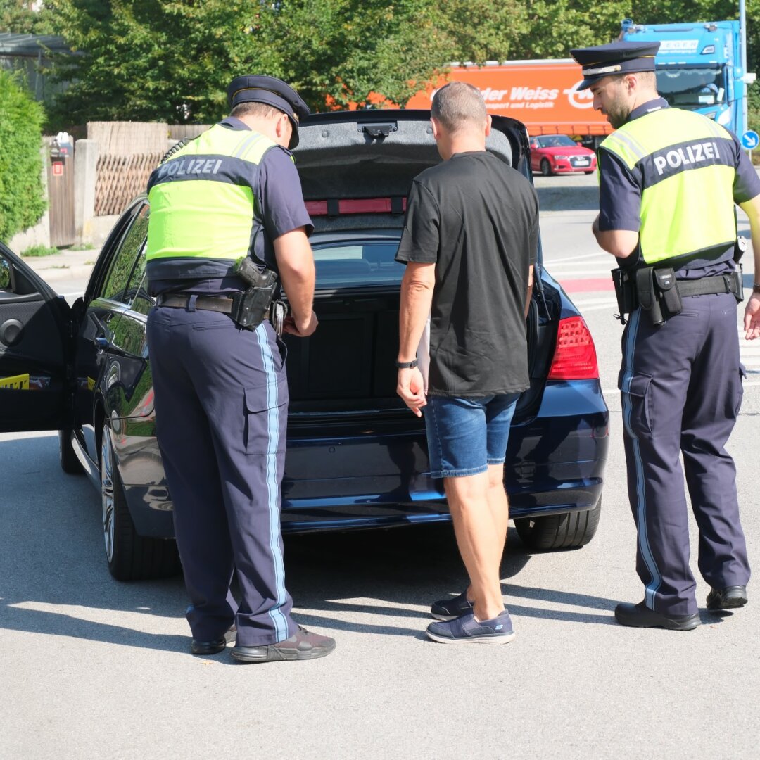 Zwei Polizisten lassen sich von einem Fahrer den Kofferraum zeigen