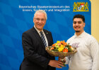 Innenminister Joachim Herrmann überreicht Eingebürgertem Blumenstrauß