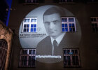 Projektion von Fliegerbauer zusammen mit den Namen der elf weiteren Getöteten auf der Gebäudefassade vor dem Haupteingang des Polizeipräsidiums München 