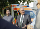 Innenminister Joachim Herrmann im Gespräch mit weiteren Personen, im Hintergrund Rettungswagen