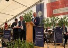 Innenminister Joachim Herrmann auf festlicher Bühne bei Rede, im Hintergrund Blasmusikorchester
