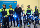 Herrmann auf Polizeirad mit Blaulicht zwischen Polizeiradlern vor Pressewand