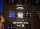 Projektion von Fliegerbauer zusammen mit den Namen der elf weiteren Getöteten auf der Gebäudefassade vor dem Haupteingang des Polizeipräsidiums München 