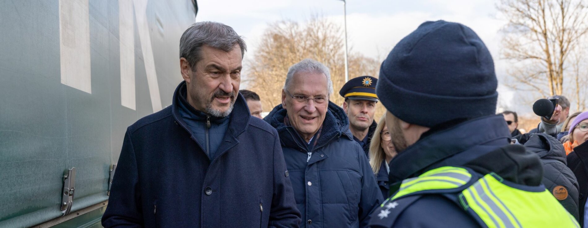 Auf dem Bild sind Ministerpräsident Dr. Markus Söder und Innenminister Joachim Herrmann gemeinsam mit einem Polizisten der Bayerischen Grenzpolizei zu sehen.