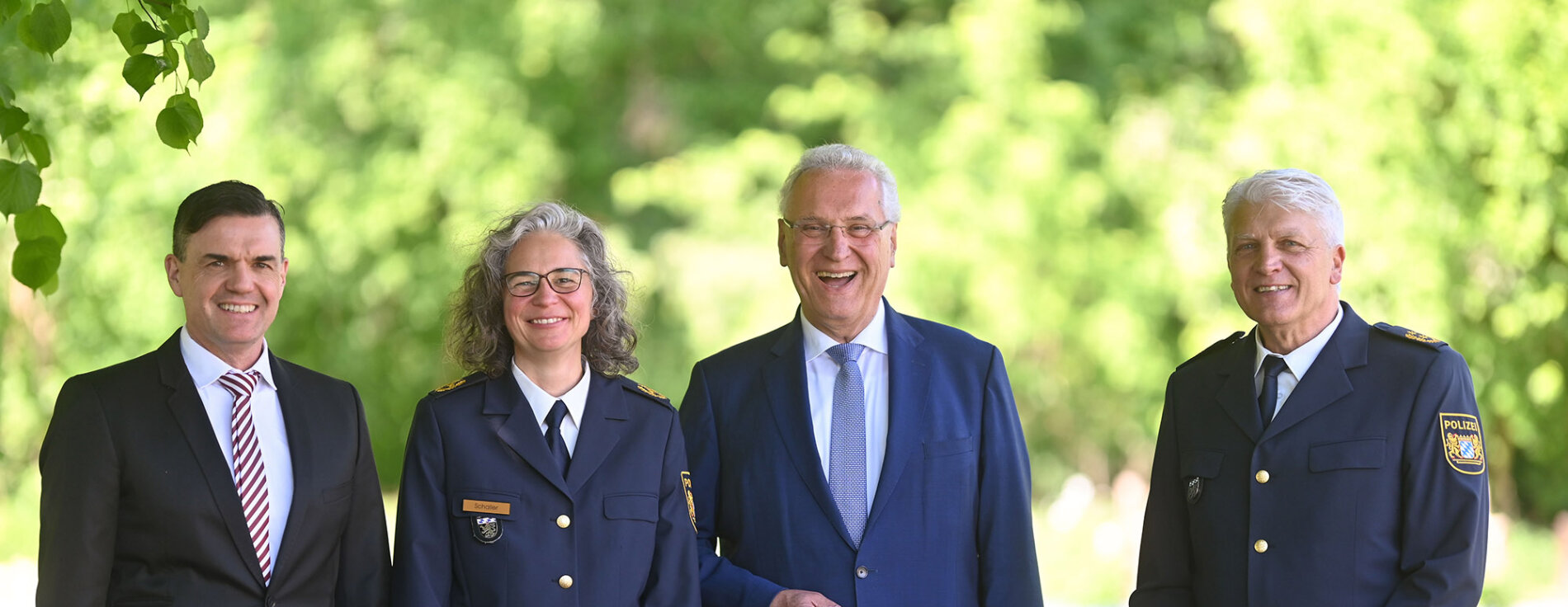 Gruppenbild (von links nach rechts:) Dirk Schmidt, neuer Polizeivizepräsident PP Oberbayern Nord, Kerstin Schaller, neue Polizeipräsidentin PP Oberbayern Nord, Innenminister Joachim Herrmann, Günther Gietl Polizeipräsident Oberbayern Nord a.D. im Hintergrund grüne Bäume