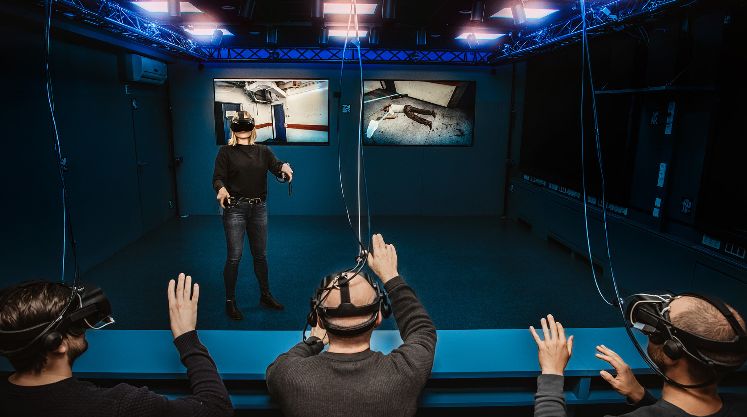 Personen mit VR-Brillen in Holodeck mit Bildschirmen