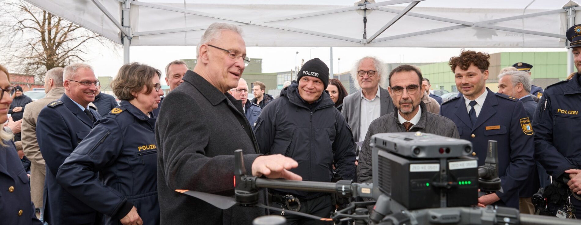 Innenminister Herrmann bei Präsentation mit vielen Menschen, im Vordergrund eine Drohne