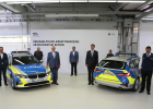 Innenminister Joachim Herrmann, Mitarbeiter von BMW sowie zwei Polizisten, bei der offiziellen Übergabe der Polizei-Einsatzfahrzeuge. Zwei Fahrzeug werden gezeigt, eines von vorne und eines von hinten.