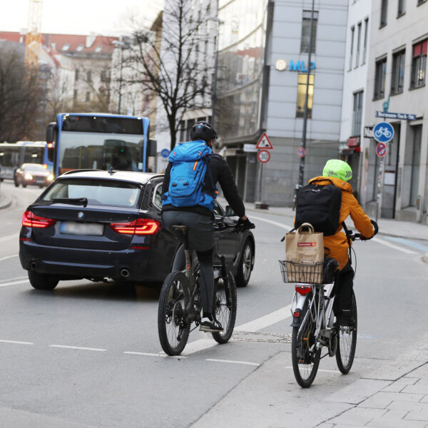 Auf dem Bild sind zwei Radfahrer von hinten zu sehen, die im Straßenverkehr in München unterwegs sind