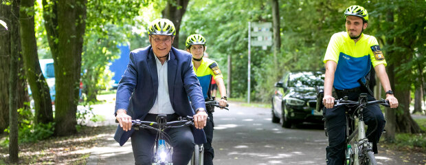 Innenminister Joachim Herrmann auf dem Polizeifahrrad neben zwei weiteren Polizisten auf Fahrrädern