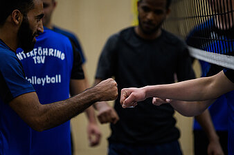 Sportler unterschiedler Hautfarbe beim Fausgruß anl. eines Volleyballspiels